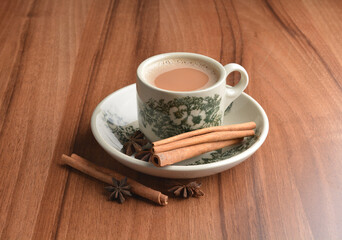 hot masala chai milk tea in traditional ceramic cup with cinnamon and star anise on wood table hot healthy asian beverage menu 