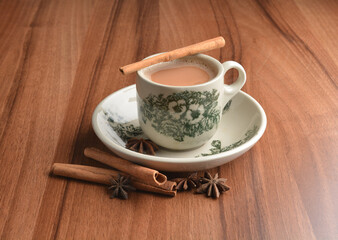 Fototapeta na wymiar hot masala chai milk tea in traditional ceramic cup with cinnamon and star anise on wood table hot healthy asian beverage menu 