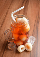 cold lychee longan fruit ice tea kombucha with white straw on wood table cocktail chilled beverage...