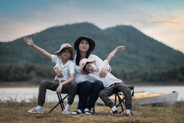Beautiful Asian mother and son doing picnic and in Easter summer party on a meadow near lake and mountain. Holiday and Vacation. People's lifestyle and Happy family life concept