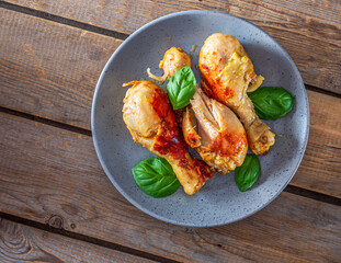 Baked chicken drumsticks with basil leaves on a gray plate