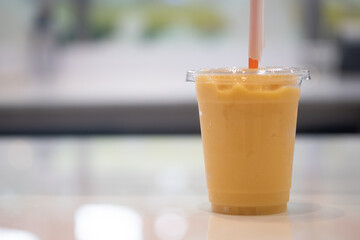 Orange, banana and mango smoothie in a plastic glass
