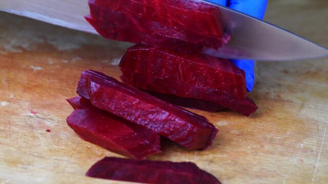 Cutting red beet root with sharp chef knife, macro shot, cooking process, preparing ingredients for eat. Close up of boiled beetroot, healthy lifestyle