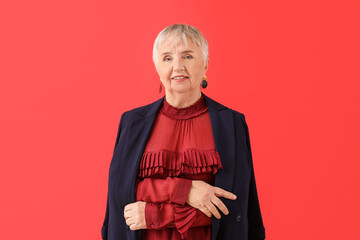 Portrait of stylish senior woman on color background