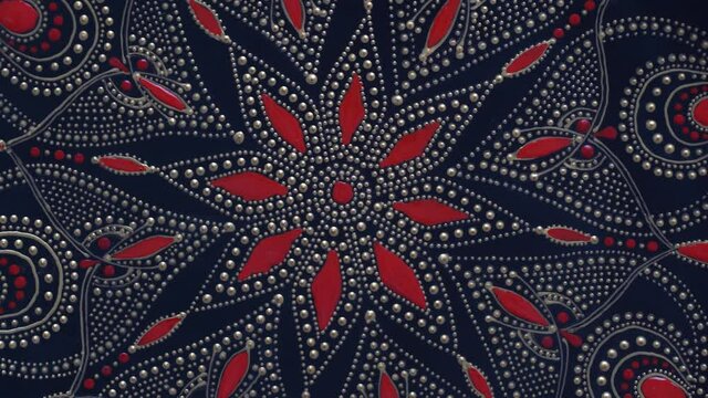 Decorative ceramic plate with black, red and golden colors, painted plate on background, closeup, top view, rotate. Decorative porcelain plate painted with acrylic paints, handwork, dot painting