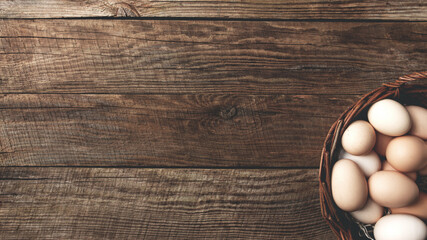 Chicken eggs in basket on wooden background. Organic household