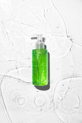 Bottle of cosmetic product in water on white background