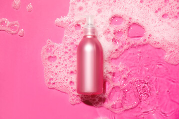 Bottle of cosmetic product in water with foam on color background