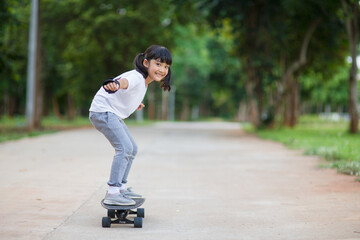 Cute little girl playing skateboard or surf skate in the skate park