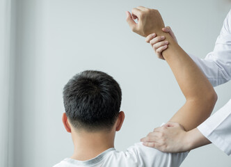 Female physiotherapists provide physical assistance to male patients with shoulder injuries massage...