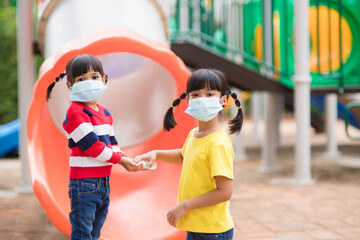 new normal lifestyle, social distancing concept. happy kids wearing face mask having fun on at playground protect coronavirus covid-19,