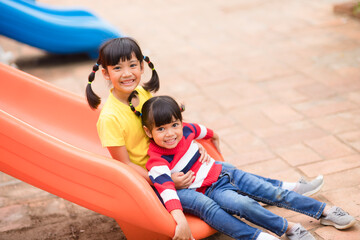 Cute little girls siblings having fun on playground outdoors on sunny summer day. Children on...