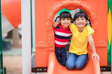 Cute little girls siblings having fun on playground outdoors on sunny summer day