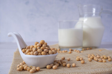 Close up tasty organic homemade soy milk in glass and soybean or soya beans in glass bowl on a wooden table background.Soy milk is a beverage made from soy.Alternative milk and healthy concept.