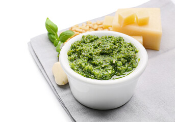 Bowl with fresh pesto sauce and ingredients on white background