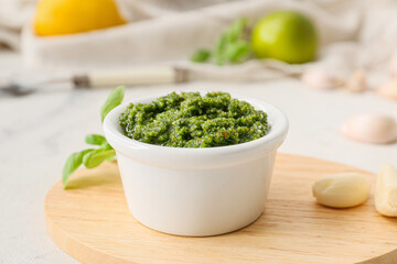 Wooden board with fresh pesto sauce and ingredients on light table