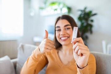Close-up shot of woman's hand holding a negative test device. Happy young woman showing her...