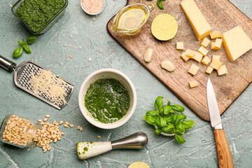 Mortar with fresh pesto sauce and ingredients on color background