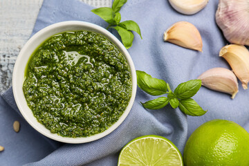 Bowl with fresh pesto sauce and ingredients on table