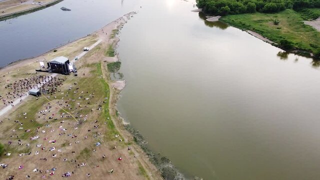 Crowd of people at music stage in Nemunas and Neris river conjunction, aerial fly over view