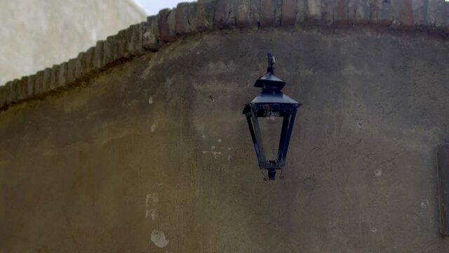 Black garden lantern on a curved brick wall