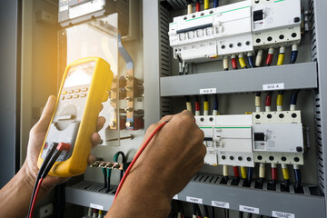 An electrician work tester measuring the voltage and current of electric power line in an electrical cabinet control.