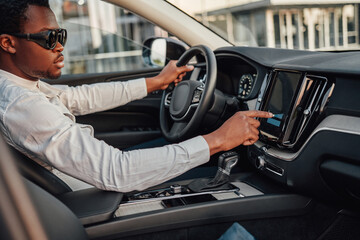 Black business man pressing on panel of car