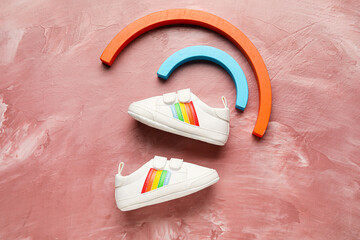 Baby shoes and toy on color background