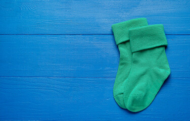 Baby socks on color wooden background