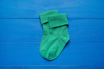 Baby socks on color wooden background