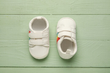 Stylish baby shoes on color wooden background