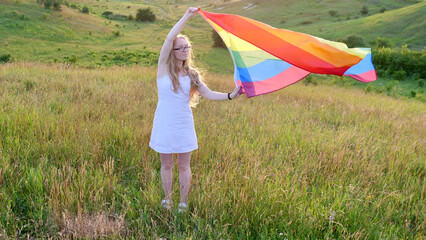 Bisexual, lesbian, woman, person, homosexual holds LGBT flag on the green hills on a sunny day sunset and celebrating a gay parade, Bisexuality Day or National Coming Out Day in pride month