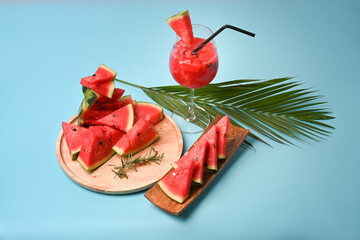 Fresh watermelon smoothie in the glass with fresh watermelon slices on blouse background.