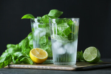 Glasses of lemonade with basil on dark background