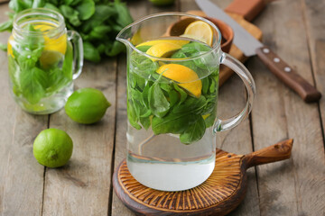 Jug of lemonade with basil on wooden table