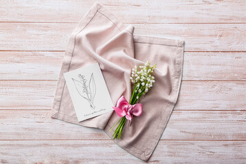 Beautiful lily-of-the-valley flowers, napkin and greeting card on wooden background