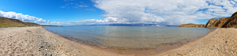 Fototapeta na wymiar Panoramic view on sandy beach of the shallow bay of Baikal Lake. Olkhon Island and the Small Sea Strait on sunny day. Beautiful summer landscape. Natural background. Travel and vacation concept