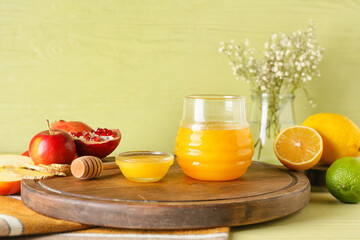 Bowl and jar of honey with fruits on color background