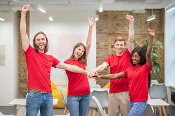 Fototapeta premium Young guys and girls happily raising their hands up