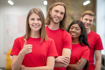 Smiling girl showing ok and friends volunteers