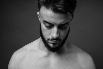 The guy whose eyes are lowered. Thick black beard in the model. Black and white photo of a guy.