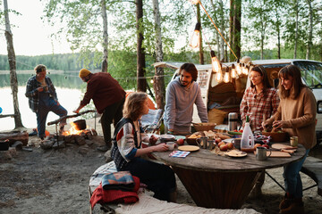 Group of friends eating and talking together on a picnic in the forest
