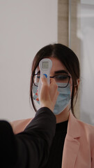 Close up of woman measuring temperature with medical thermometer to prevent covid 19. Coworkers...
