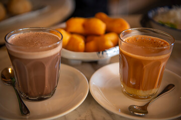 Close up Hot coco and hot thai tea with blurred deep-fried doughstick (patongko) 
