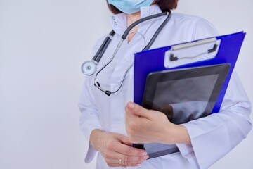 Female doctor with stethoscope with clipboard and digital tablet, on light background
