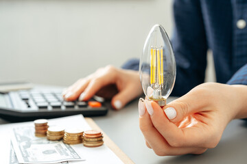 Female hand holding a light bulb above the table