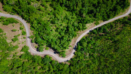 aerial top view of curves roadway pass through fresh green forest on mountain, road path on hill 