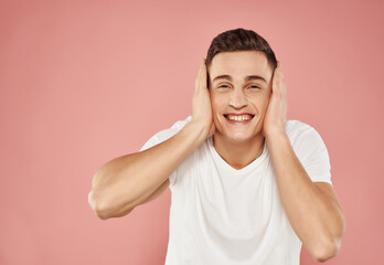 cheerful man gesturing with his hands in a white t-shirt on a pink background