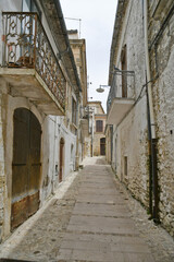 Fototapeta na wymiar Bovino, Italy, 06/23/2021. A narrow street among the old houses of a medieval town with a Mediterranean style in the Puglia region.