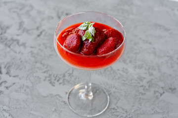 Fresh strawberry fruit parfait in glass cup on gray surface
